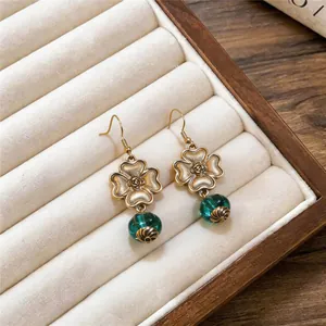 Close-up detail of vintage floral earrings with emerald green beads in a jewelry box