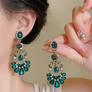 Close-up of vintage emerald green waterdrop earrings with floral diamond accents