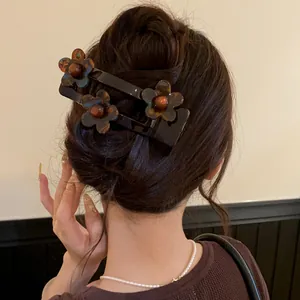 Close-up of a French acrylic flower hair clip worn in an elegant bun hairstyle detail