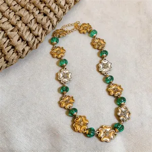 Vintage court style necklace featuring gold flower charms and green beads detail on texture