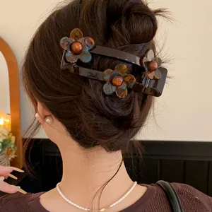 Detail view of a French acrylic flower hair clip with tortoiseshell pattern on hair bun