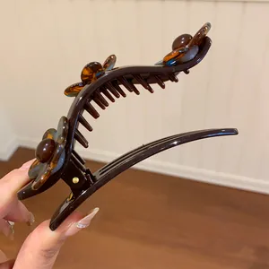 Detailed side view of a brown acrylic flower duckbill hair clip with tortoise shell texture.