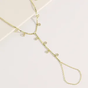 Détail d'un bracelet bague minimaliste en or avec des breloques pendantes en zircon