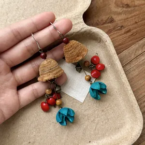 Detailed view of ethnic style wooden earrings with red beads and blue floral accents.