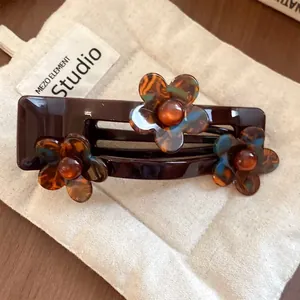 Close-up of an acrylic French hair clip with tortoiseshell flowers on a beige fabric pouch
