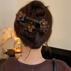 Detail showing a stylish brown acrylic flower hair clip worn on elegant hair bun styling.