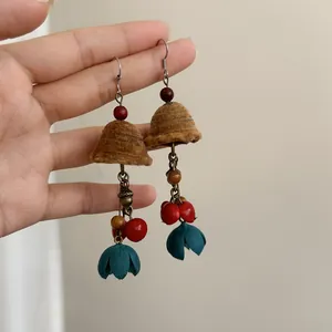 Detailed macro view of ethnic style wind chime earrings with brown flocking and teal petals
