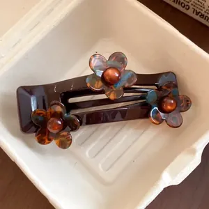 Detail shot of a dark brown French acrylic hair clip with tortoise shell floral motifs
