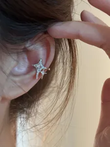 Detailed view of a sparkling silver-toned zircon star ear cuff worn on the ear bone cartilage