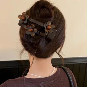Detailed view of an elegant French acrylic floral duckbill hair clip on styled hair