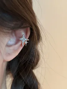 Detailed view of a sparkling zircon star ear cuff on a model's ear, silver-toned finish.