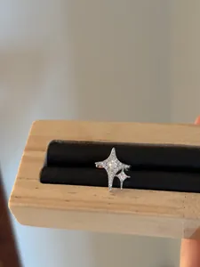 Close-up view of 14K gold plated silver star ear cuff with cubic zirconia on wooden stand.