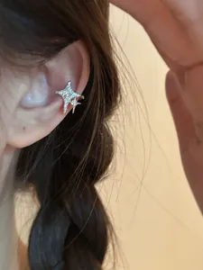 Close-up detail of a sparkling 14K gold plated star ear cuff shown on a model ear.