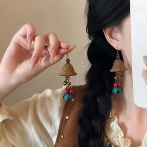 Detailed view of ethnic style vintage wooden flocked bell earrings with teal tassels and retro style
