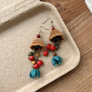Detail view of ethnic wind chime earrings with brown flocked bells and blue tassels