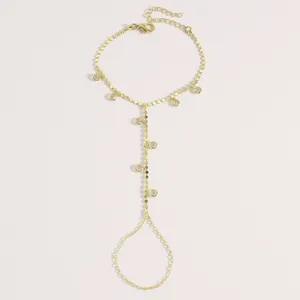 Vue détaillée d'une chaîne de main dorée avec pendentifs en zircon et anneau de doigt.