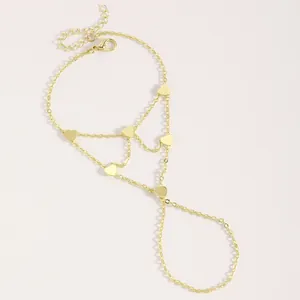 Vue détaillée d'un élégant bracelet de main doré avec petits cœurs et chaîne réglable