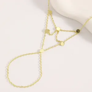Bracelet bague doré avec breloques rondes minimalistes sur un fond blanc très épuré