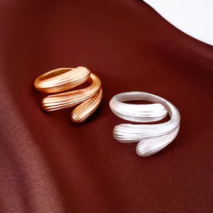 Makroaufnahme von geometrisch texturierten offenen Ringen in Gold- und Silberoptik