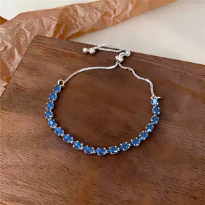 Détail d'un bracelet argenté ajustable orné de zircons bleus en forme de goutte