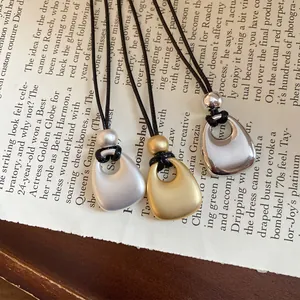 Detailed close-up view of metal pendant necklaces with matte and shiny finishes on a book