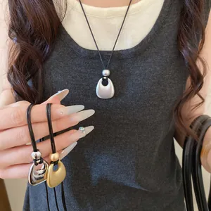 Detail shot of minimalist cord necklaces with matte and glossy metal pendants on a model