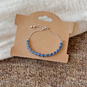 Gros plan d'un bracelet en argent avec zircons bleus sur une carte en kraft