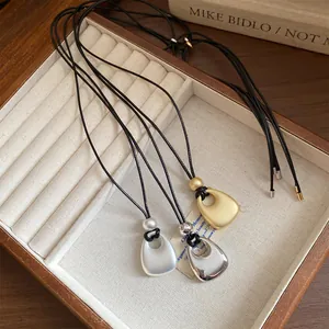 Close-up of three minimalist metal necklaces with leather cords in a jewelry tray