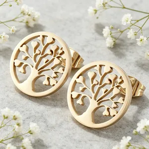 Détail de boucles d'oreilles Arbre de Vie évidées dorées sur texture de pierre