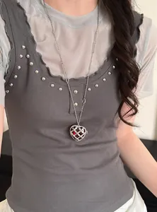 Detailweergave van een Koreaanse hartjesketting met rode steen op een model.
