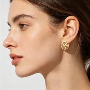 Détail d'une boucle d'oreille ronde dorée en forme d'arbre de vie sur l'oreille du mannequin