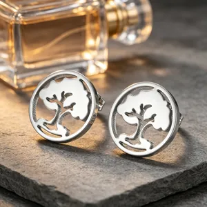 Gros plan de boucles d'oreilles puces rondes ajourées Arbre de Vie sur une ardoise