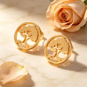 Vue détaillée des boucles d'oreilles Arbre de Vie dorées avec rose sur marbre.