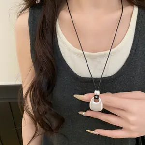 Detail view of a minimalist Korean leather cord necklace with a matte metal pendant