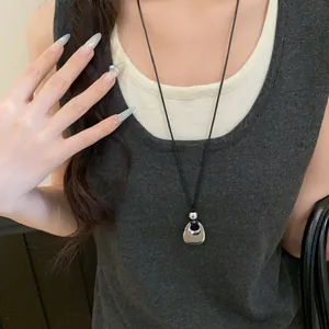Close-up of a minimalist Korean-style metallic pendant necklace with a black cord
