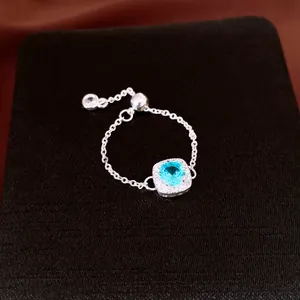 Gros plan d'une bague chaîne ajustable en argent avec un zircon bleu carré.