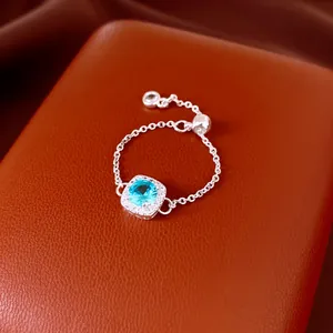 Gros plan sur une bague chaîne réglable en argent avec zircon bleu carré central