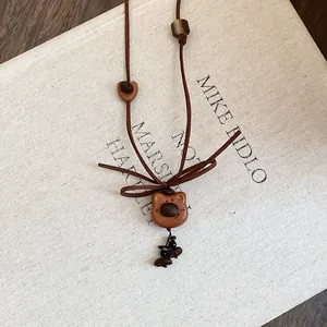 Close-up of a handmade wooden bear pendant necklace with brown suede cord and coffee bean beads.