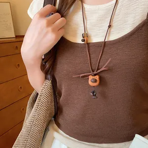 Close-up of a cute wooden puppy pendant necklace worn with a brown knitted sweater