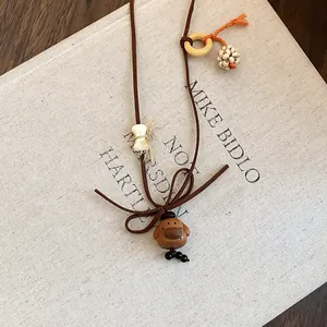 Macro view of a cute wooden dog pendant on a brown cord necklace laid over a beige book.