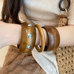 Gros plan de trois bracelets en bois rétro de différentes largeurs portés au poignet