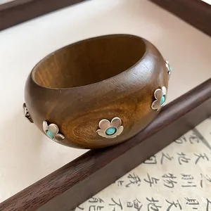 Gros plan d'un bracelet en bois vintage avec des fleurs en argent et touches turquoises