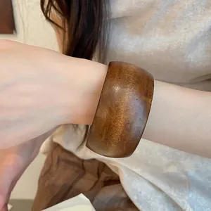 Vue détaillée d'un large bracelet en bois rétro avec une finition marron lisse au poignet