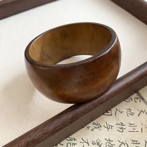 Gros plan détaillé d'un bracelet jonc en bois foncé vintage au grain naturel.