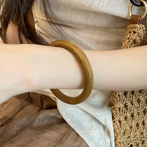 Gros plan d'un bracelet jonc rond en bois de style vintage porté sur le poignet d'un mannequin
