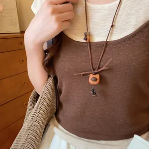 Close-up of a cute wooden bear pendant necklace with a brown suede cord on a model