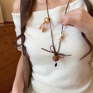Model wearing a cute wooden puppy pendant necklace with a brown cord on a white top