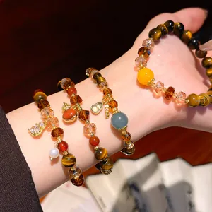 Close-up detail of vintage Maillard tiger eye and crystal beaded bracelets worn on the wrist