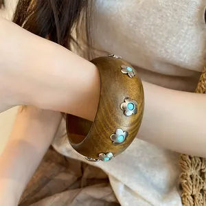 Vue détaillée d'un jonc en bois rétro avec incrustations de fleurs turquoise porté au poignet