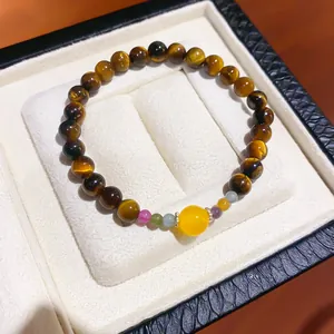 Macro view of a tiger eye beaded bracelet with colorful accents in a white jewelry box.